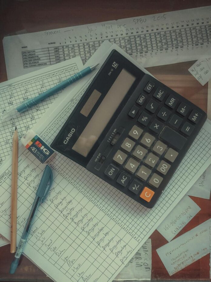 Bills and calculator used to compare debt repayment methods